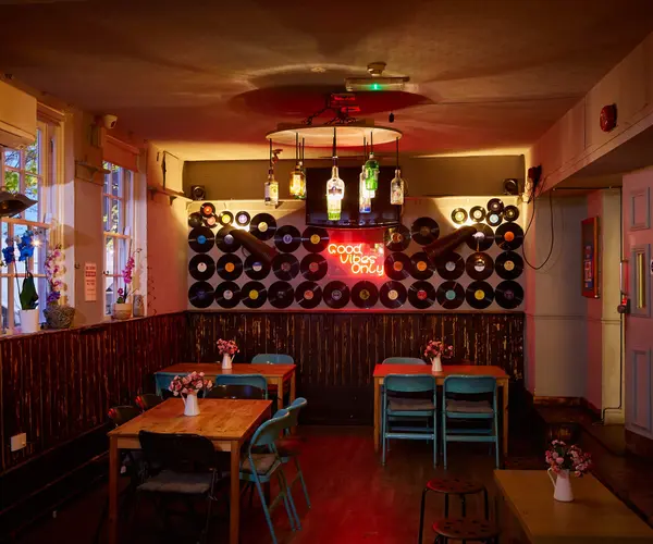 Dining area with a wall of vinyl records and a Good Vibes Only neon sign