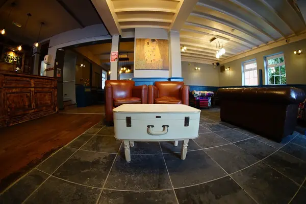 Open-plan lounge with leather armchairs and flagstone floor