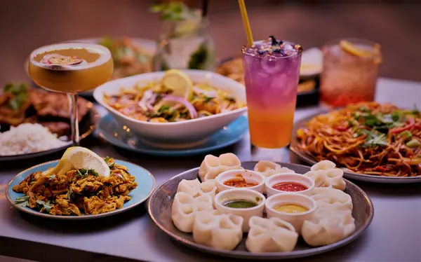 Steamed momo with four dipping sauces alongside pakora and noodles