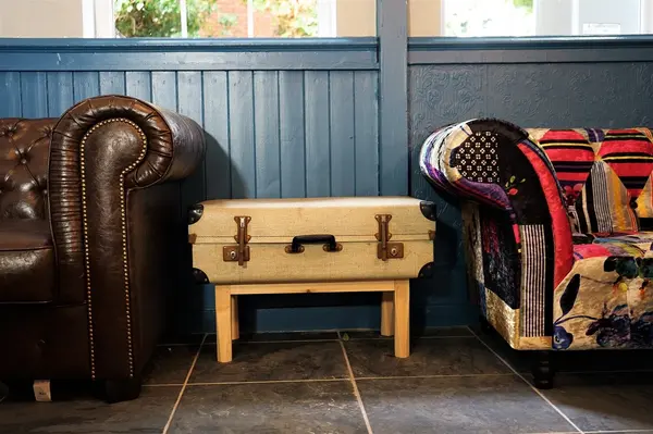 Leather Chesterfield sofa and patchwork armchair beside blue panelled walls